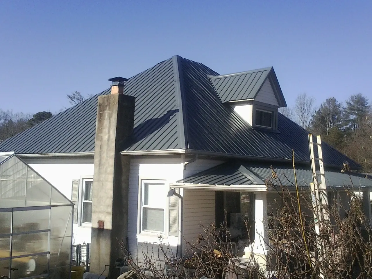 Dark blue standing seam metal roof on a white farmhouse with dormer — Slate & Tile Roof Repair by Roofing Brothers in Dawson Springs