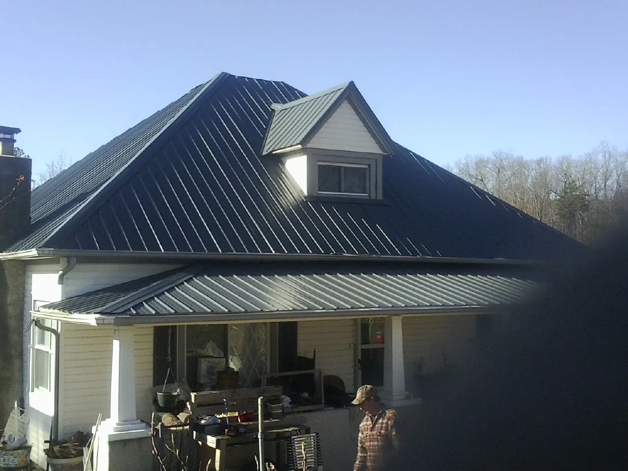 Dark blue standing seam metal roof with a dormer above a front porch in Dawson Springs