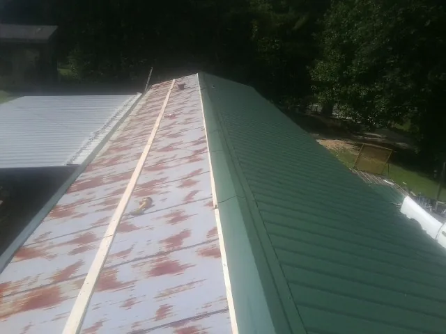 Old rusted panels beside newly installed green metal roofing — Wind Damage Roof Repair by Roofing Brothers in Dawson Springs