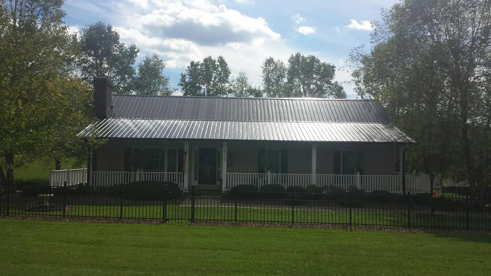 Gray metal roof on a brick ranch with a full width front porch — Gutter Guard Installation work by our crew in Dawson Springs