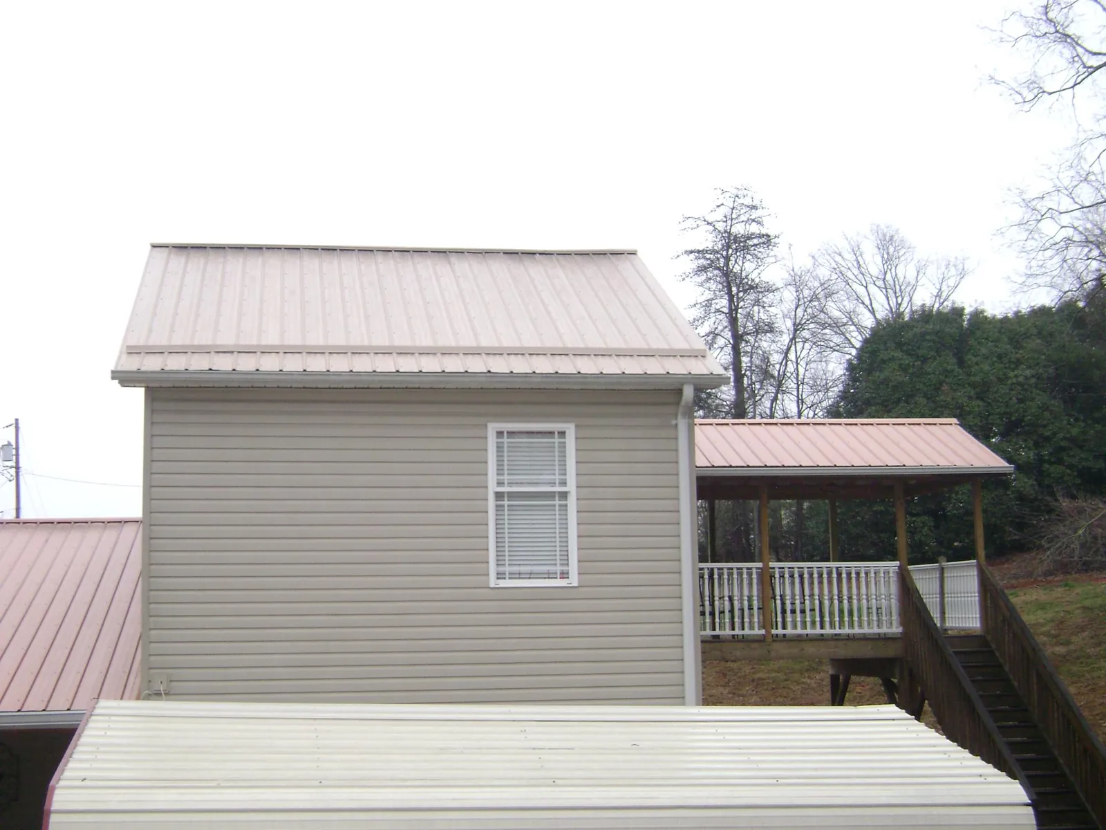 Tan metal roofs on a two story addition and attached porch, from a Roof Replacement job in Dawson Springs