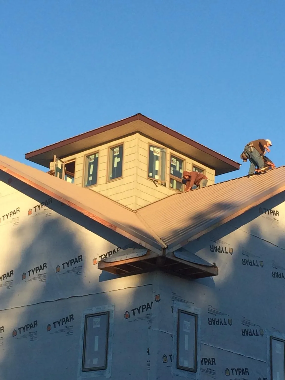 Roofers working around a rooftop cupola on a new metal roof at sunset — Roof Waterproofing in Dawson Springs by Roofing Brothers